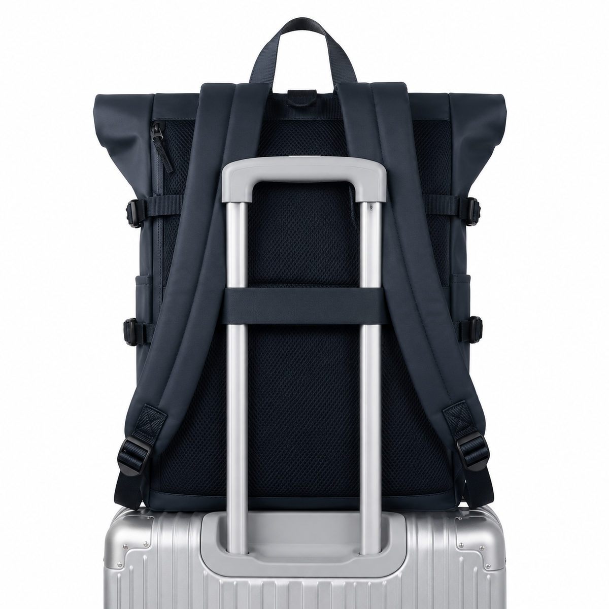 Sac à dos roll-top bleu marine vu de dos, enfilé sur la poignée télescopique d'une valise argentée