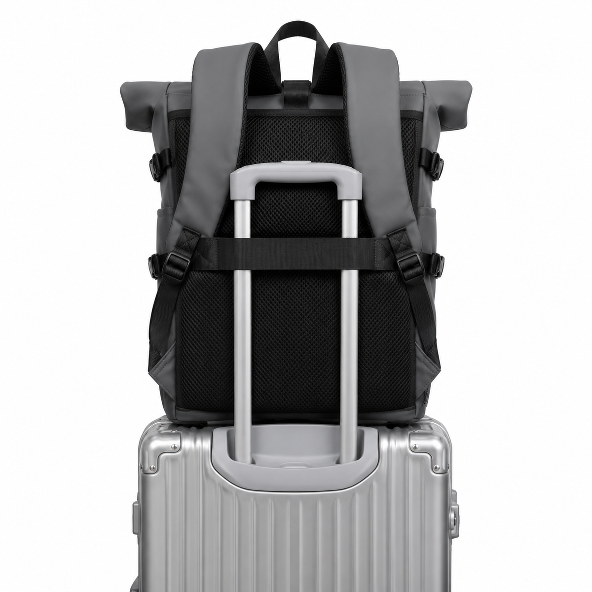Sac à dos roll-top gris foncé vu de dos, enfilé sur la poignée télescopique d'une valise argentée